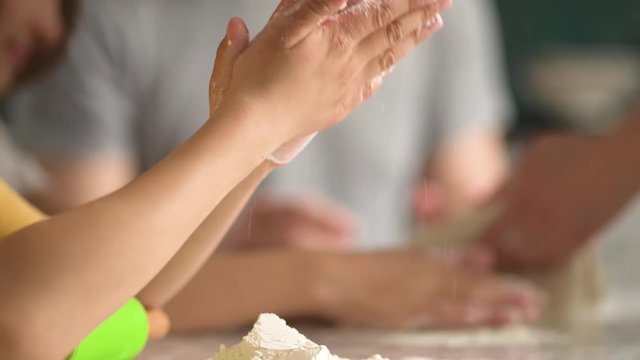 Children cooks pizza. Boy and girl having fun with father. Prepering ingredients for pizza. Close view of the hands of a child in flour.