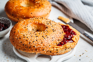 Bagels with peanut butter and berry jam on white board. Vegan food concept.