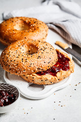 Bagels with peanut butter and berry jam on white board. Vegan food concept.