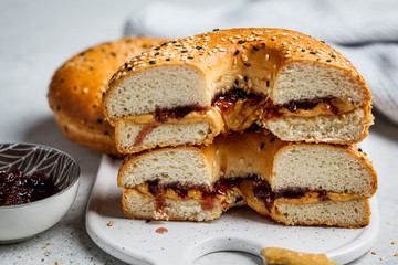 Bagels with peanut butter and berry jam on white board. Vegan food concept.