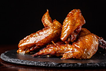 American cuisine. Fried chicken wings glazed in honey sauce on a black background. background image, copy space text