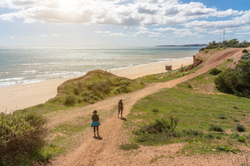 Two girls athletes in sports uniforms, walk along the cliff shore, in the summer near the sea. Beach of Falesia, Vilamoura Albufeira, Portugal.
