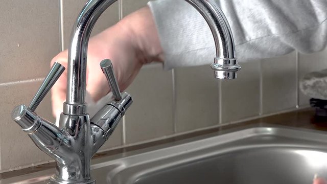 Polishing water tap at steel kitchen sink