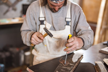 Male carpenter working on old wood in a retro vintage workshop.