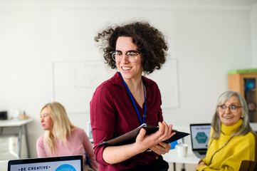 Portrait of teacher with seniors attending computer and technology education class.