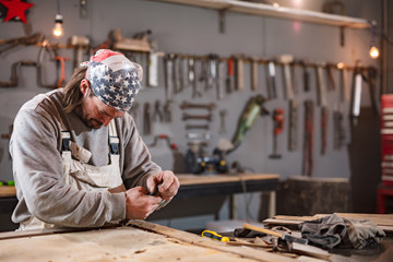 Male carpenter working on old wood in a retro vintage workshop.