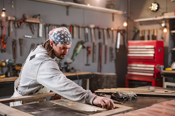 Male carpenter working on old wood in a retro vintage workshop.