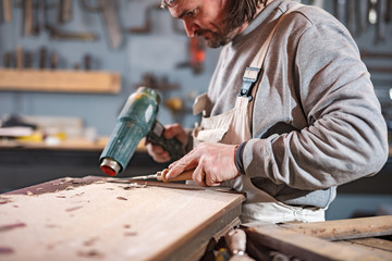 Male carpenter working on old wood in a retro vintage workshop.