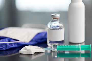 medicine and healthcare concept - close up of syringe, drug, wound wipes, gloves and mask on table