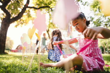 Fototapeta premium Small children outdoors in garden in summer, playing.