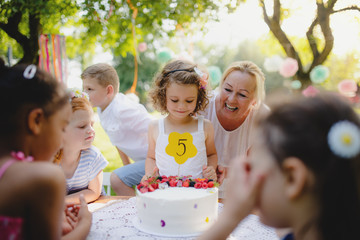 Small girl's birthday party outdoors in garden in summer, celebration concept.