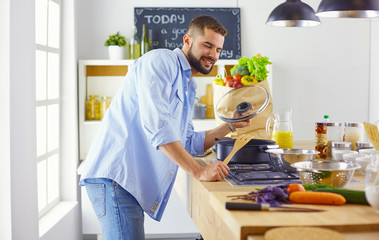 Smiling and confident chef standing in a large kitchen tasting a cooked dish