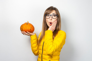 young girl with a surprised face holds on a light background. Halloween concept, autumn, celebration