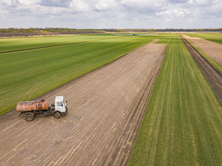 Aerial drone photo. Green meadow farmland field with sprayer truck.