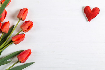 Red tulips and hearts on the white table, background blank for postcards. Copy space.