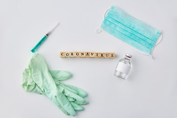 medicine, healthcare and epidemic concept - coronavirus word on wooden toy blocks , protective mask, gloves and syringe with drug on white background