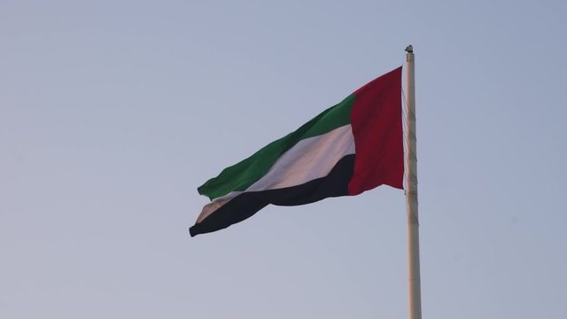 Slow motion view of the national flag of United Arab Emirates blowing in the desert wind at sunset.