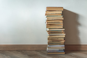 Big stack of old books over white wall, education concept, with copy space