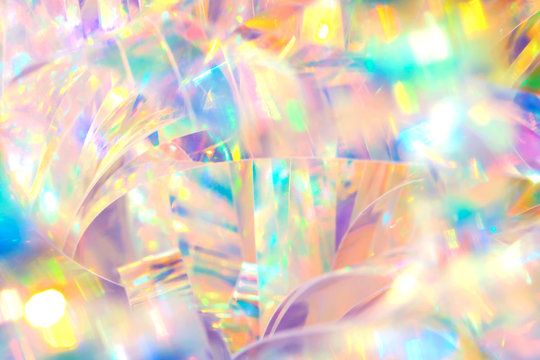 Abstract radiant cheerful disco fun wallpaper image of festive holographic foil ribbon with bright gleaming pastel colored sparkling crystal reflections and blurred bokeh light effect