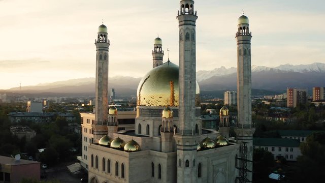 Aerial flight around mosque with gold dome at sunrise in Almaty city , Kazakhstan