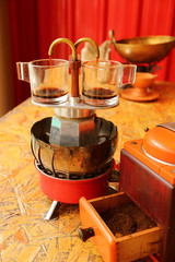 Two cups of espresso being brewed with a mini retro coffee maker with a grinder in foreground