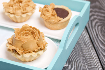 Chocolate ganache tartlets and cakes. Decorated with oil cream flowers. The cream has a caramel color.