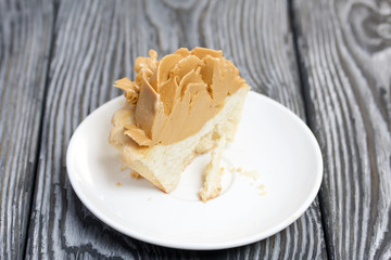 Half a cake decorated with butter cream flowers. The cream has a caramel color. On brushed pine boards painted black.