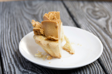 Half a cake decorated with butter cream flowers. The cream has a caramel color. On brushed pine boards painted black.