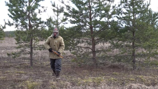 Man hunter soldier Red Army going forest shoots firing a sawn-off shotgun, gun