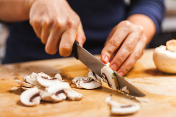Woman cutting fresh organic mushrooms on chopping board, making healthy low calories salad.