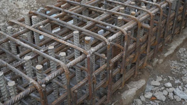 closeup foundation isnot completely poured with concrete. open frame made of steel reinforcement for laying foundation pit in residential building.