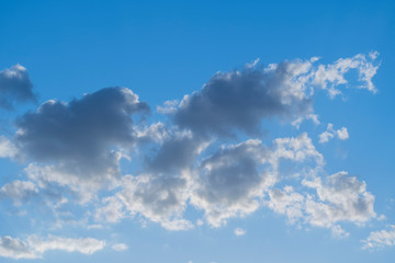 White clouds against a blue spring sky at sunset day