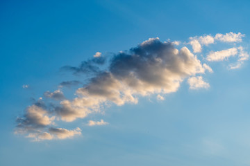 White clouds against a blue spring sky at sunset day
