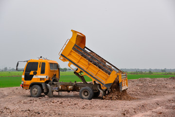 The truck is dumping soil at a construction site