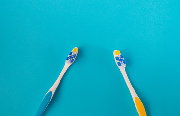 two toothbrushes blue and yellow on a blue background