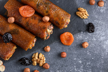 vegan snack, fruit pastille with nuts, honey, dried fruits on gray background, Turkish sweets, healthy dessert concept