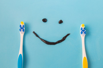 two plastic colored toothbrushes and a tube of funny smile from a black toothpaste