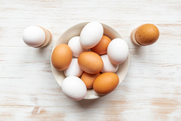Free-range organic brown and white eggs in bowl on wood background with copy space