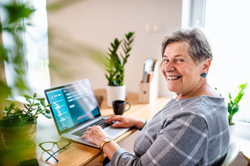 Senior woman with laptop working in home office.