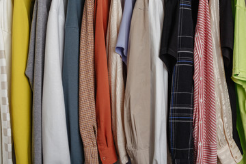 Close-up view of clothes hung on hangers, variety of clourful sleeves in photo