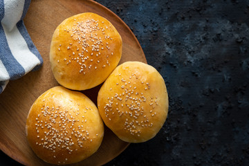 Homemade burger buns with sesame seeds isolated on a dark blue background