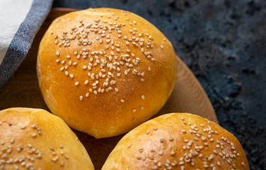 Close up of fresh baked homemade burger buns covered with sesame seeds isolated on a blue background