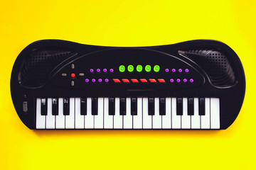 Portable electronic keyboard on yellow background . Toy synthesizer.
