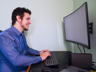 Young caucasian programer man laughing in front of the computer