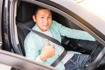 Young asian man smiling and showing thumb up in his car. Travel concept, Safety first insurance concept