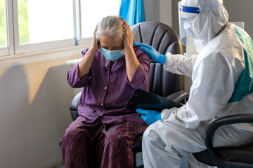 Asian doctor wear PPE suit talk with old female patient about disease symptom, elderly health check up , they wear surgical mask with Providing comfort and encouragement for the elderly.