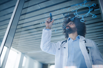 Fototapeta premium Doctor making notes in hospital, corona virus concept. Shot through glass.
