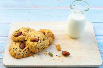 Milk and cookies on a wooden tray placed on a wooden table.