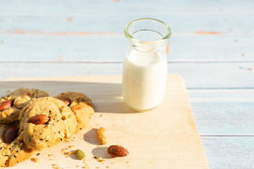Milk and cookies on a wooden tray placed on a wooden table.