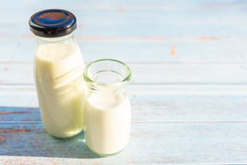 Milk glass and bottle on wooden table with copy space.